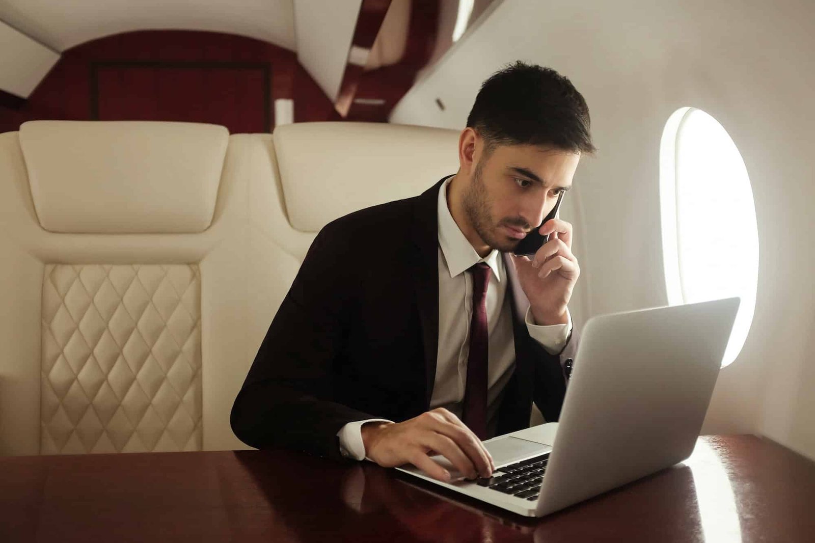 Billionaire or rich businessman flying first class and working on plane with laptop