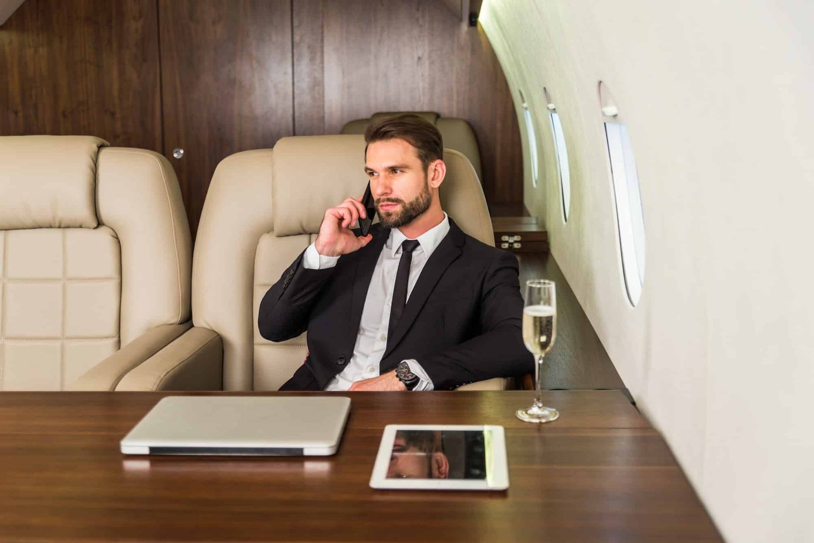 Man in a black dress talking on the phone in a private jet in London