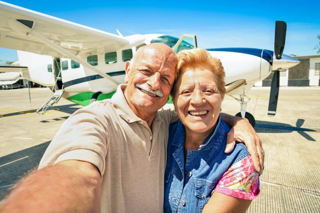 Senior happy couple taking selfie with private ultralight plane for tour around the world