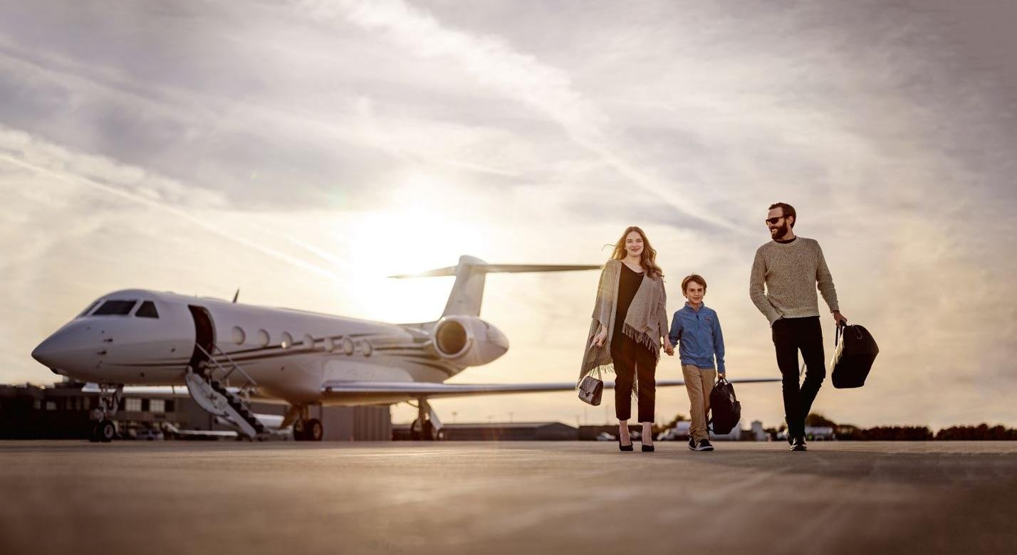 A woman walking with her son and husband away from the private jet