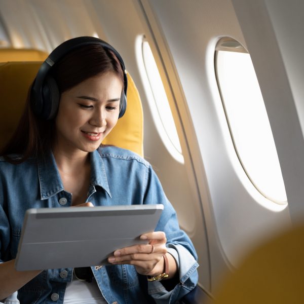 Beautiful asian travel woman watching movie on digital tablet in airplane.