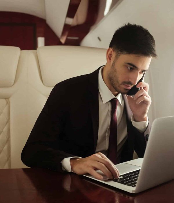 Billionaire or rich businessman flying first class and working on plane with laptop