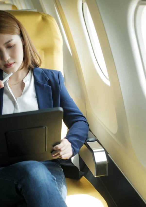 Business woman working on tablet while sitting in airplane.