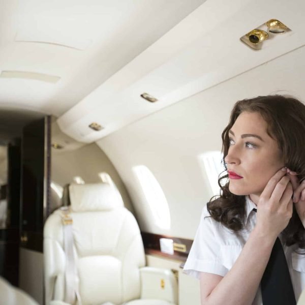 Female flight attendant putting on earring in cabin of private jet