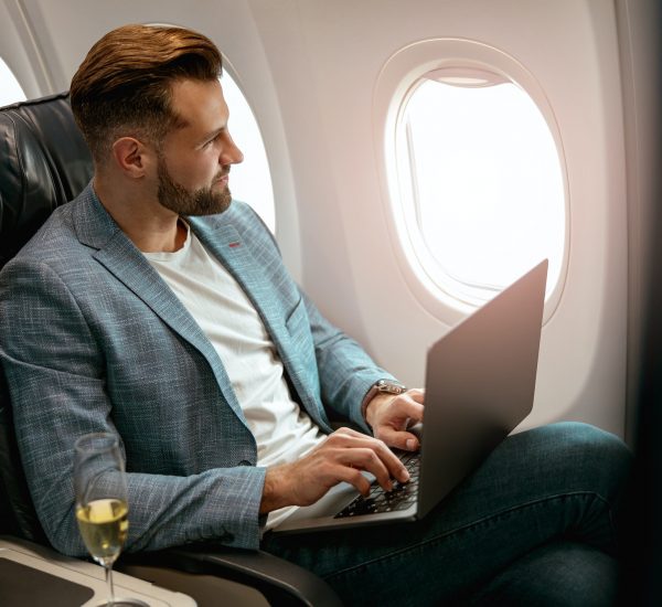 Male passenger working on laptop in airplane
