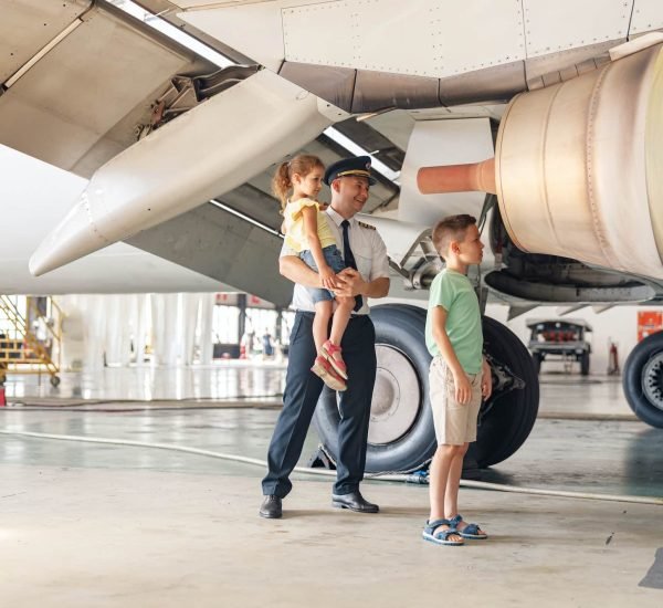 Pilot in uniform showing parts of airplane an their functions to two little kids