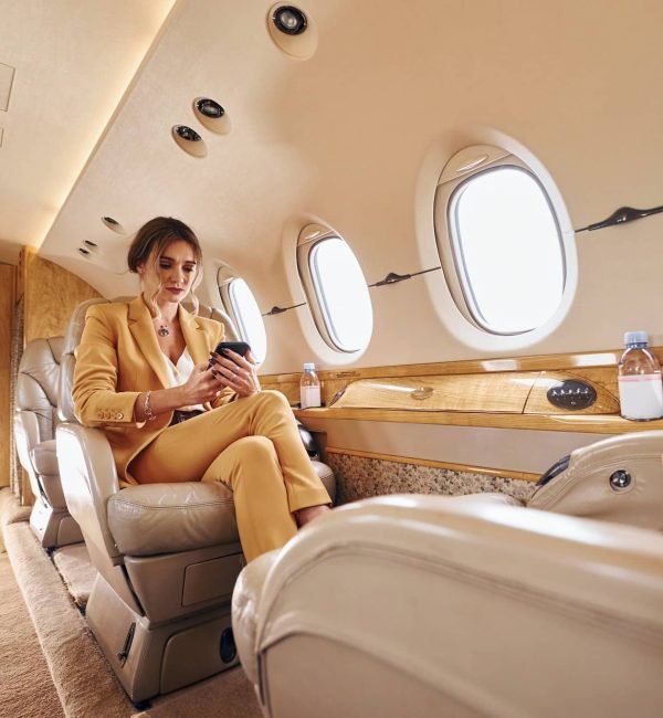 Woman in yellow clothes sits inside of private airplane